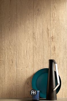 a plate, vase and other items are sitting on a shelf in front of a wood paneled wall