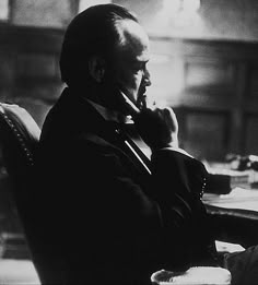 a man sitting at a desk talking on a cell phone