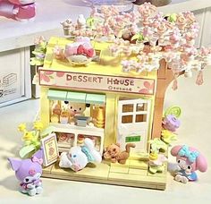 there is a small toy store with little animals around it on the table and other toys