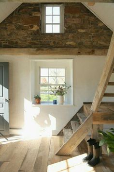 a wooden staircase leading up to a window in a room with stone walls and beams