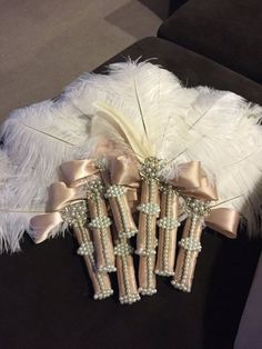 three wedding garters with white feathers and pearls on them sitting on a couch