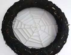 a close up of a black wreath with white tiles in the shape of a spider's web