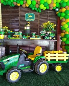 a green tractor with yellow wheels parked in front of a party decoration