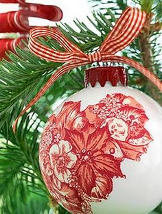 a red and white ornament hanging from a christmas tree with ribbon on it