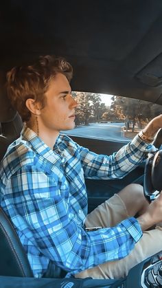 a man sitting in the driver's seat of a car with his hand on the steering wheel