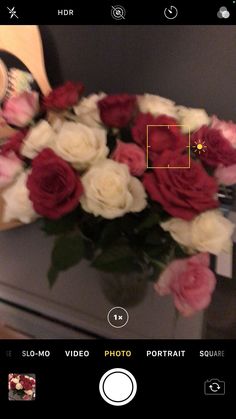 a bouquet of roses sitting on top of a table next to a camera and cell phone