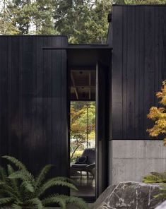 an open door leading into a black house surrounded by trees