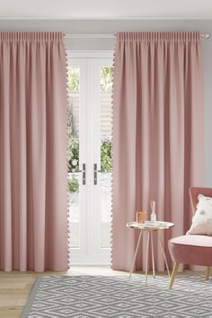 a living room with pink curtains and furniture