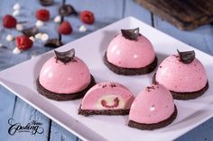 four desserts on a white plate with chocolate and raspberry frosting in the middle