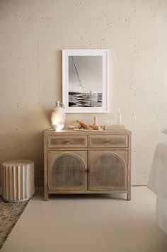 a white bed sitting next to a wooden cabinet with pictures on the wall above it