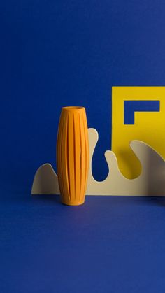 an orange vase sitting on top of a blue table next to a yellow letter f