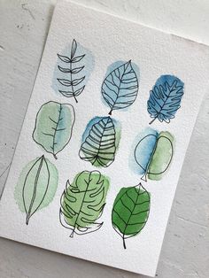 a watercolor painting of different leaves on a white paper with green and blue ink