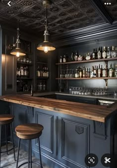 a bar with two stools in front of it and several bottles on the shelves