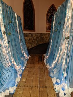 a wooden floor covered in snow next to a wall with lights on it and blue drapes covering the walls