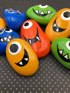 painted rocks with monster faces on them sitting on a polka dot tablecloth covered surface