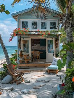 a small house on the beach with chairs and flowers