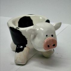 a ceramic cow shaped cup sitting on top of a white countertop next to a black and white wall