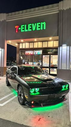 a black car is parked in front of a 7 eleven seven store with green lights