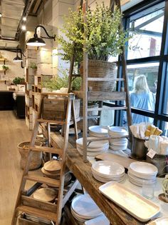 a room filled with lots of white plates and bowls on top of wooden shelves next to windows