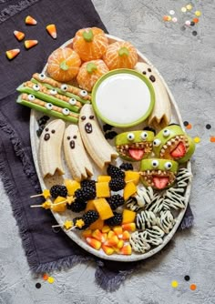 an assortment of halloween treats on a plate with candy corn, oranges and bananas