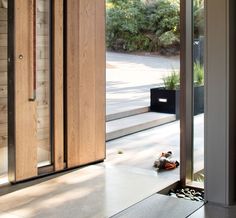 an open wooden door in front of a large glass window on the side of a building