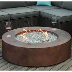 a fire pit sitting on top of a wooden deck next to two glasses of wine