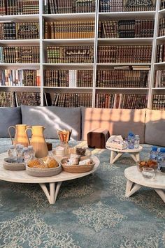 two tables with food on them in front of a bookshelf full of books