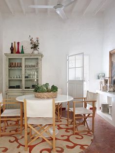 a white table and chairs in a room with an area rug on the floor next to it