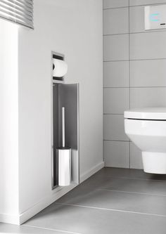 a white toilet sitting next to a wall mounted paper dispenser