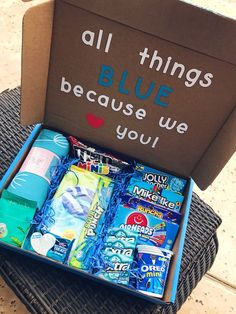 an open box with various items inside sitting on a wicker chair next to a sign that says, all things blue because we love you