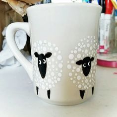 a white coffee cup with black sheep painted on the side and polka dots around it