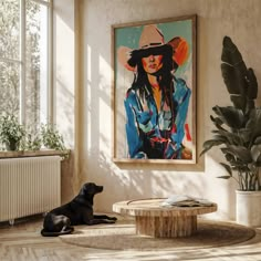 a black dog laying on the floor in front of a painting and potted plant