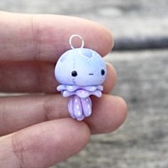 a tiny blue and purple octopus charm sitting in someone's hand with it's eyes closed