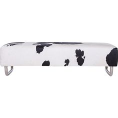 a cow print bench with metal legs and black spots on white fabric, sitting in front of a white background