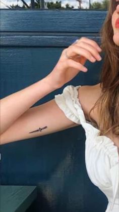 a woman with a small tattoo on her left arm and right arm behind her head