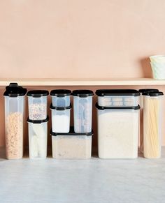 an assortment of food containers lined up on a shelf in front of a pink wall