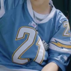 a young man sitting down wearing a jersey