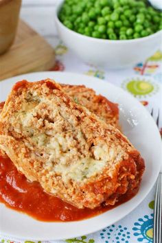 two meat patties on a plate with sauce and peas