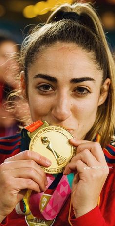 a woman holding a gold medal in front of her face