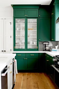 a kitchen with green cabinets and white counter tops, wood flooring and wooden floors