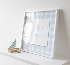 a white shelf with a wooden toy boat on it and a blue gingham background