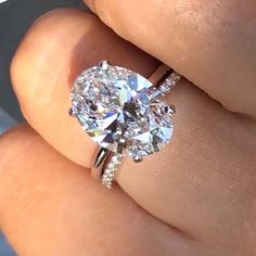 a woman's hand with a diamond ring on top of her finger and an oval shaped diamond in the middle