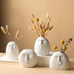 three white vases with flowers in them sitting on a table next to each other