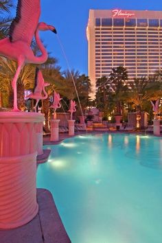 the flamingo statue is next to an empty swimming pool in front of a hotel