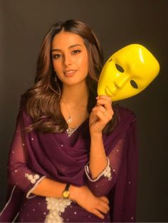 a woman holding a yellow mask in front of her face