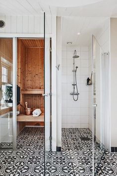 a bathroom with black and white flooring and wooden paneled walls, along with a walk in shower