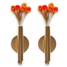 two metal vases with flowers in them on a wall