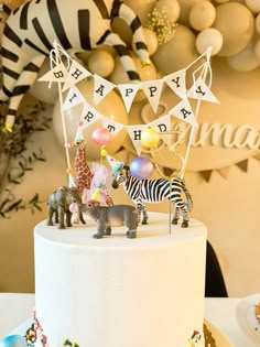 a birthday cake with zebras and giraffe figurines on top is shown