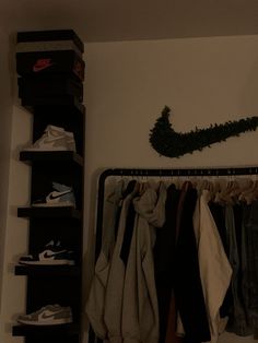 a closet filled with clothes and shoes next to a wall mounted shoe rack on the wall