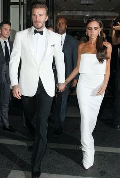 a man and woman dressed in white walking together